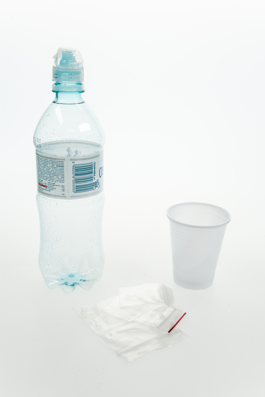 Fotografia przedstawia plastikową butelkę, plastikowy kubek i woreczki foliowe.