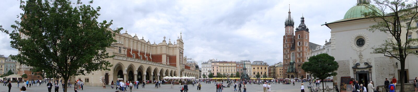 Ilustracja przedstawia Rynek Główny Starego Miasta, gdzie znajdują się Sukiennice. Ich cechą charakterystyczną są arkady umieszczone na parterze. Budowla zwieńczona jest attyką. Przy północno‑wschodnim narożniku Starego Miasta stoi Bazylika Mariacka. Kościół ma dwie wieże: wyższą, z której grany jest hejnał, i niższą. W wysmukłych murach są umieszczone ostrołukowate okna. Zdobią je motywy  roślinne, a zworniki rzeźbami figuralnymi. Wokół rynku przeważają kamienice, w których mieszczą się kawiarenki. 