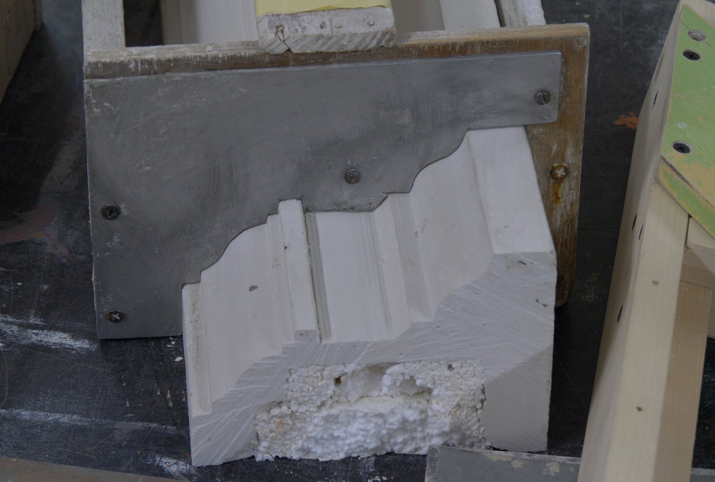 Zdjęcie przedstawia wykrój do gzymsów. Wykrój jest wykonany z metalu. Jego kształt odpowiada kształtowi gzymsu widocznego na zdjęciu.