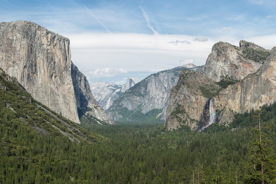 Fotografia przedstawia fragment gór w Sierra Nevada w Stanach Zjednoczonych. Góry mają kształt dużych bloków. Na dole porośnięte są drzewami. 
