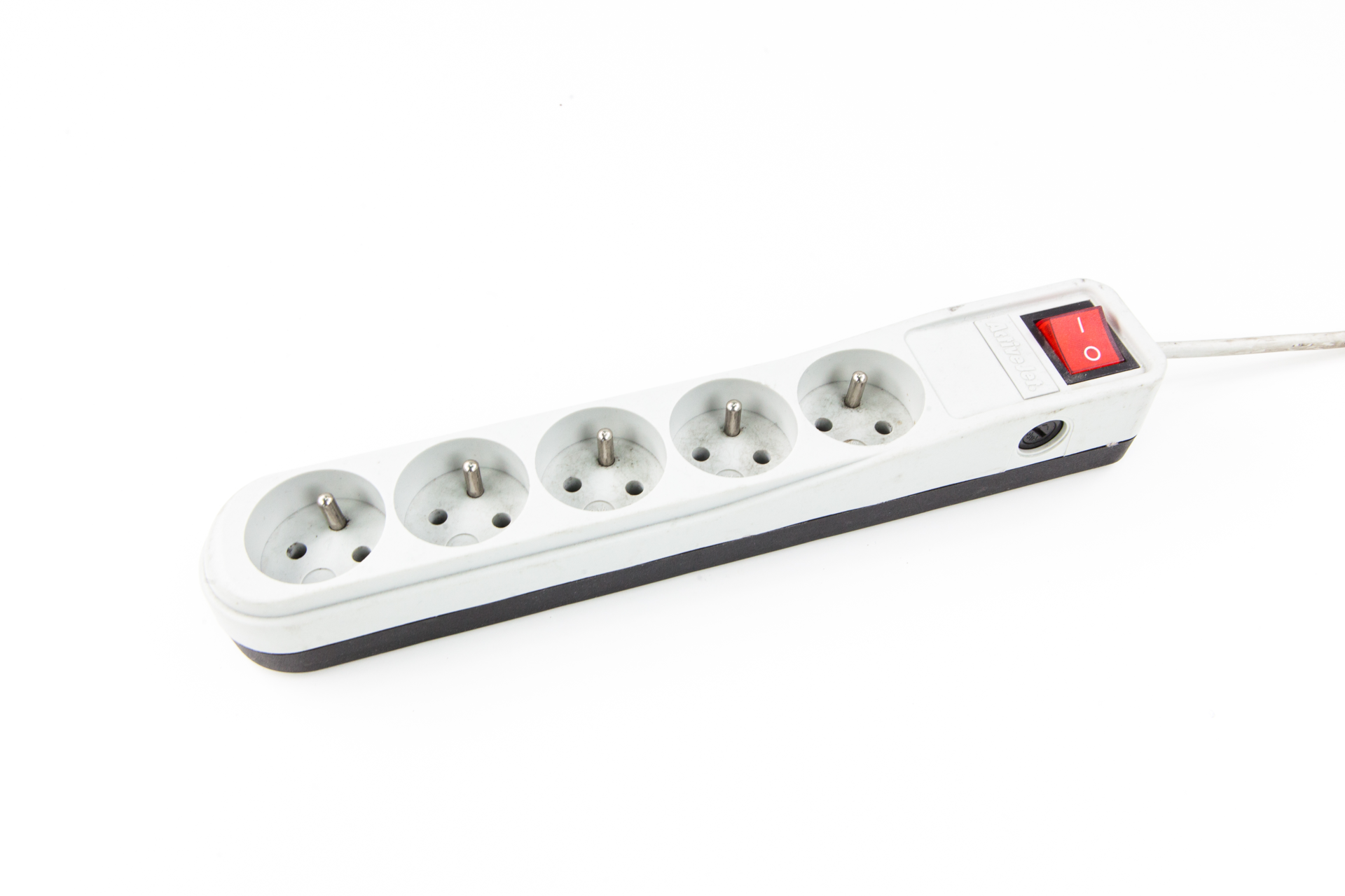 Fotografia przedstawia podłużną, wąską listwę zasilającą, zbudowaną z pięciu gniazdek wystającymi metalowymi bolcami, oraz czerwonego, kwadratowego włącznika.  Listwa jest wyłączona. Z prawej strony listwy wystaje kabel. 