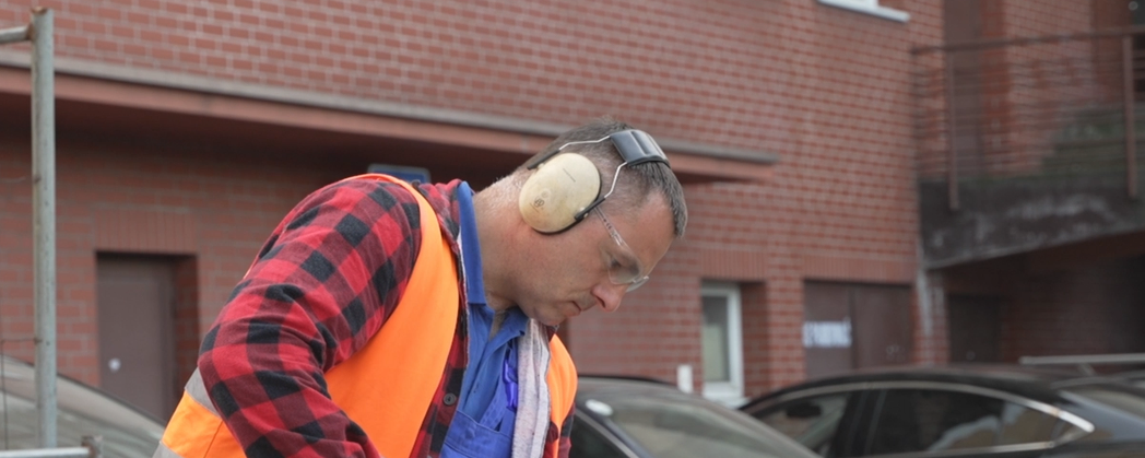 Na grafice przedstawiono pracownika noszącego słuchawki ochronne chroniące przed nadmiernym hałasem.