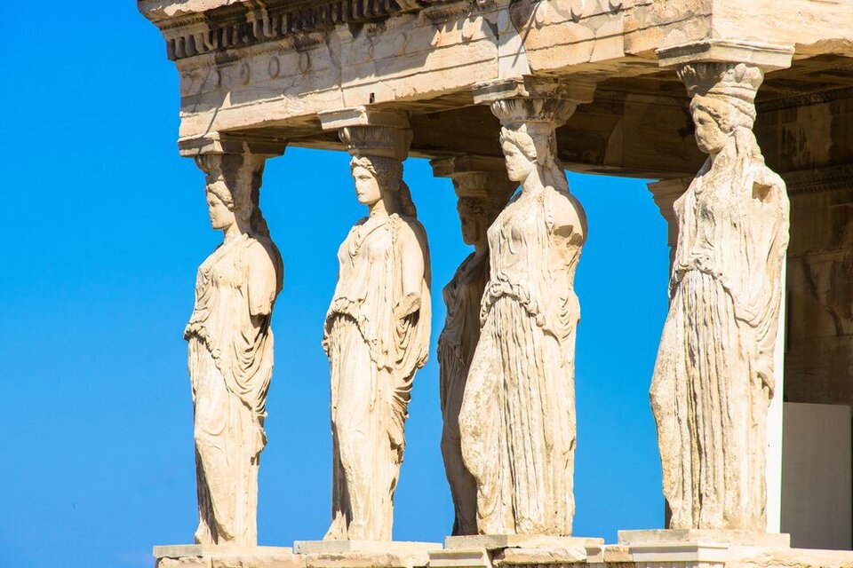 Ilustracja przedstawia fragment Erechtejonu z południowym portykiem, którego częścią jest kolumnada z kariatyd. Posągi podpierają strop, są to figury sztywno stojących kobiet z opuszczonymi wzdłuż ciała rękoma, ubrane w swobodne szaty. 