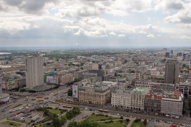 Zdjęcie przedstawia panoramę miasta. Po lewej stronie znajduje się ogromne rondo. Zaraz za nim bardzo wysoki budynek. Po prawej stronie rozciąga się widok na kamienice i blokowiska.