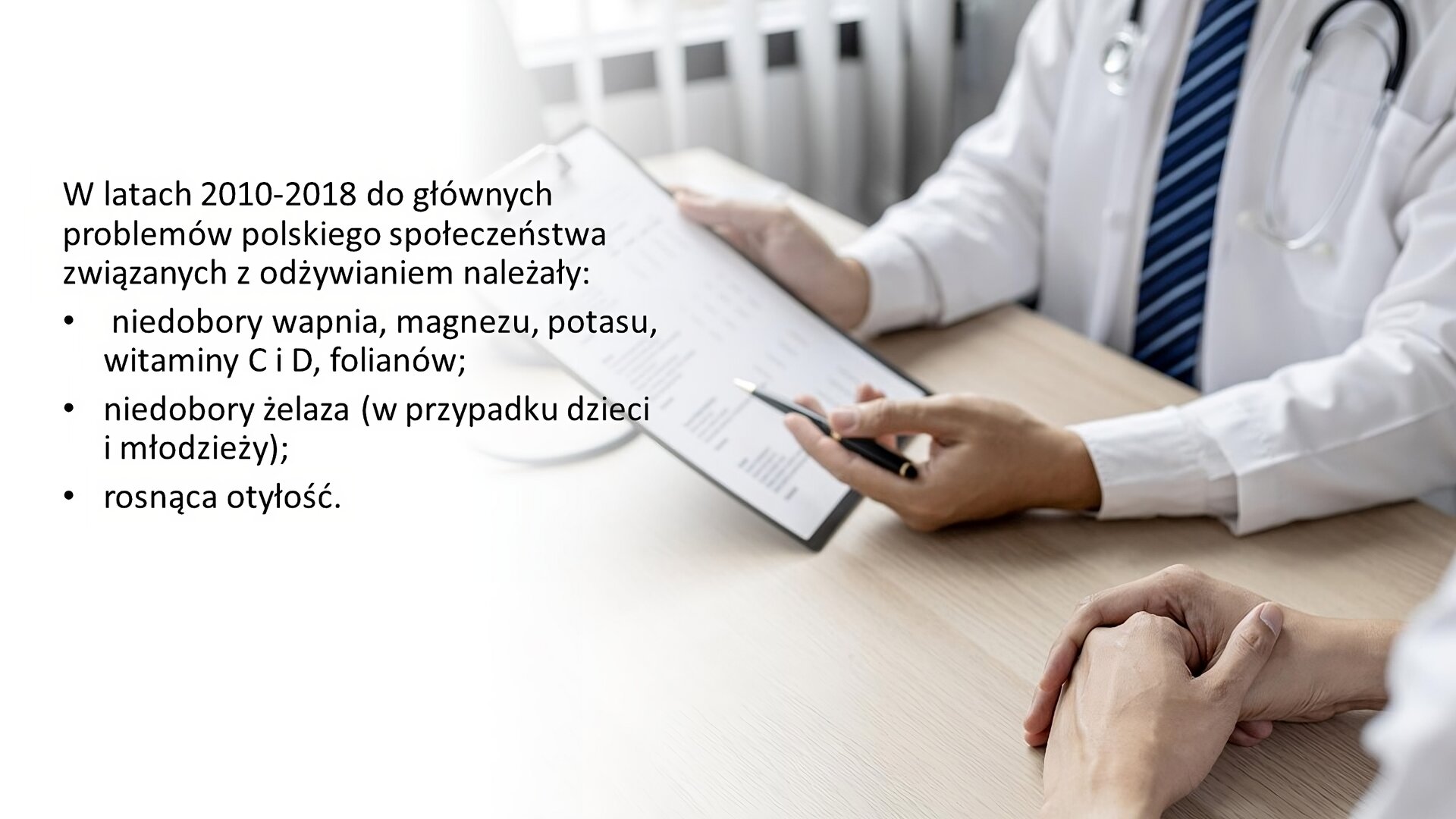 Biały slajd. Z prawej strony slajdu zdjęcie przedstawia mężczyznę w kitlu, który w prawej dłoni trzyma podkładkę z dokumentami, a w lewej długopis. Obok niego dłonie kobiety. Z lewej strony slajdu tekst: „W latach 2010‑2018 do głównych problemów polskiego społeczeństwa związanych z odżywianiem należały: niedobory wapnia, magnezu, potasu, witaminy C i D, folianów; niedobory żelaza (w przypadku dzieci i młodzieży); rosnąca otyłość”.