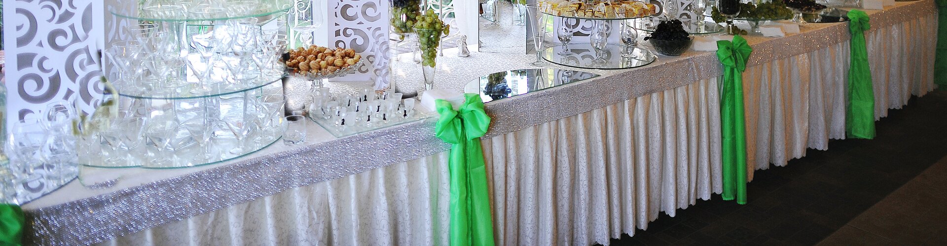Zdjęcie przedstawia przykładowe użycie skirtingu. Widoczny jest pod skosem stół bufetowy przykryty białym obrusem, z doczepioną falbaną sięgającą podłogi, dekorowaną w równych odstępach zielonymi kokardami. Na stole widoczne są pojemniki, nakrycia, przekąski.