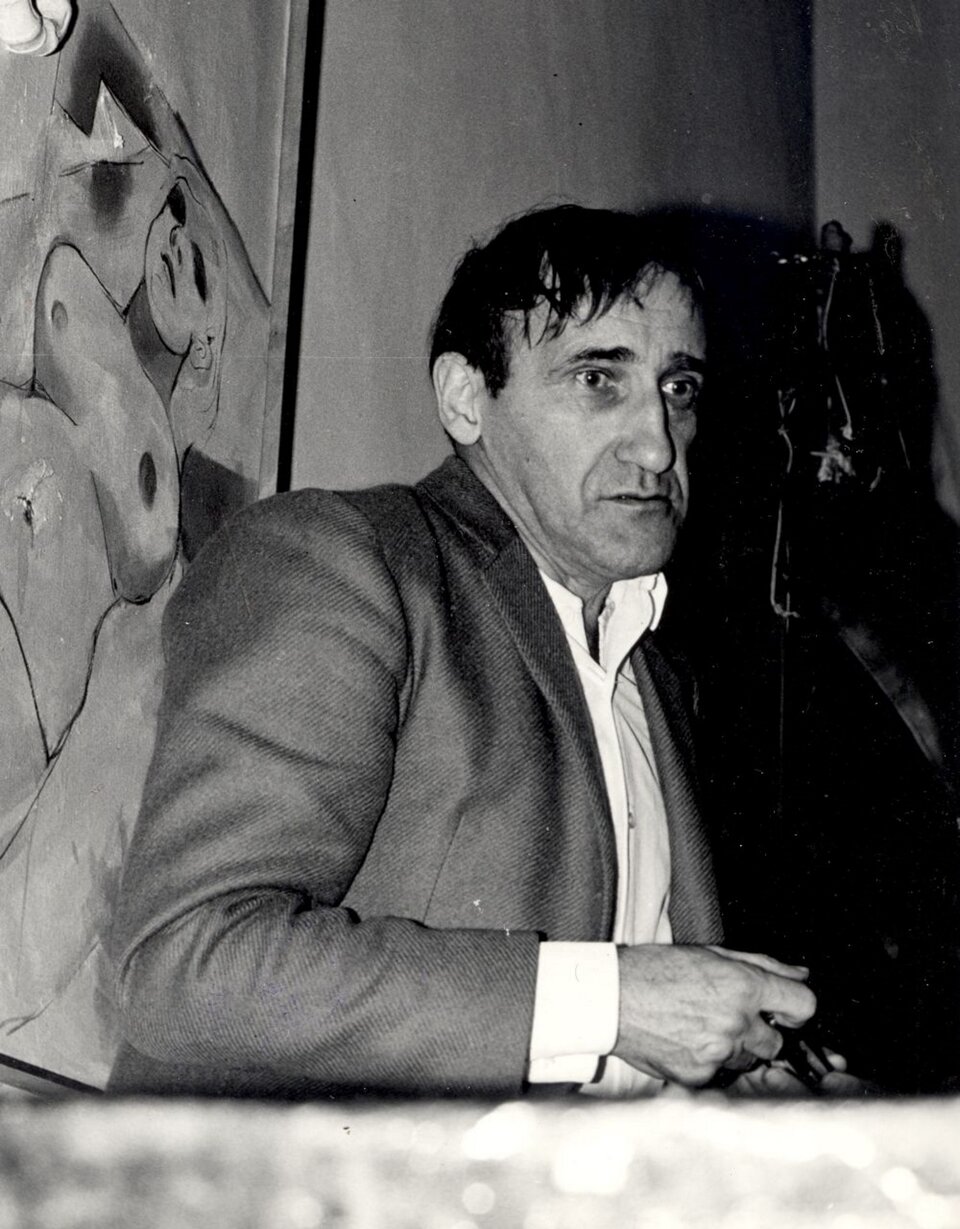 Ilustracja przedstawia czarno‑białe zdjęcie Tadeusza Kantora. Mężczyzna ma zdziwiony i zmęczony wyraz twarzy. Ubrany jest w białą koszulę i szarą marynarkę.