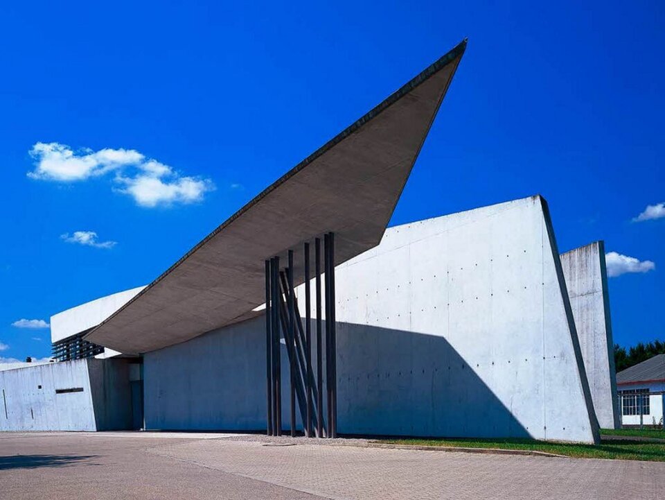 Ilustracja o kształcie poziomu prostokąta przedstawia remizę strażacką fabryki mebli Vitra Zaha Hadid. Fotografia ukazuje budynek od strony ulicy. Posiada on wąski, podłużny kształt, dostosowany do położenia przyulicznego. Nad wejściem znajduje się ukośne zadaszenie wsparte na metalowej konstrukcji. Fasada składa się z nieforemnych brył o różnych wielkościach, posiada prosty, zgeometryzowany kształt.