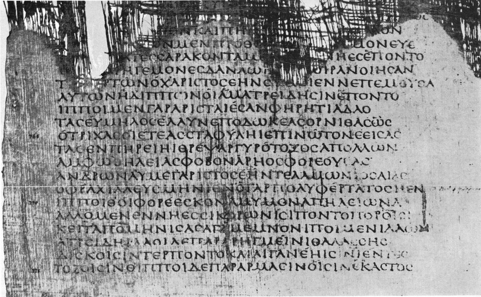 Na czarno‑białej fotografii znajduje się papirus z tekstem "Iliady" napisanej greką. Papirus jest zniszczony w swojej górnej części. 
