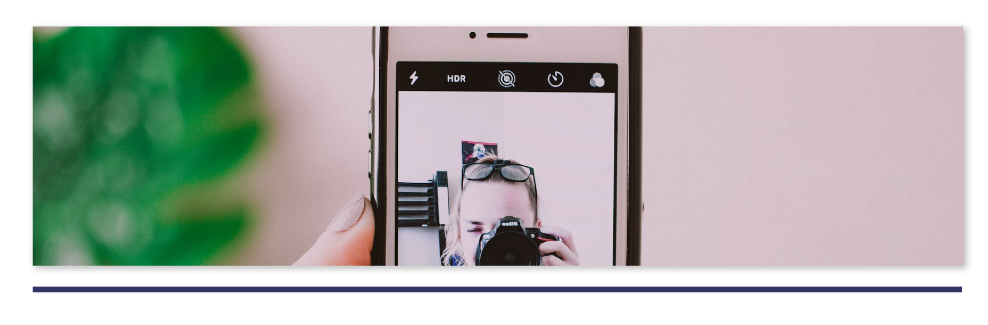 Ilustracja przedstawia fragment smartfona ze zdjęciem kobiety robiącej zdjęcie aparatem na wyświetlaczu.