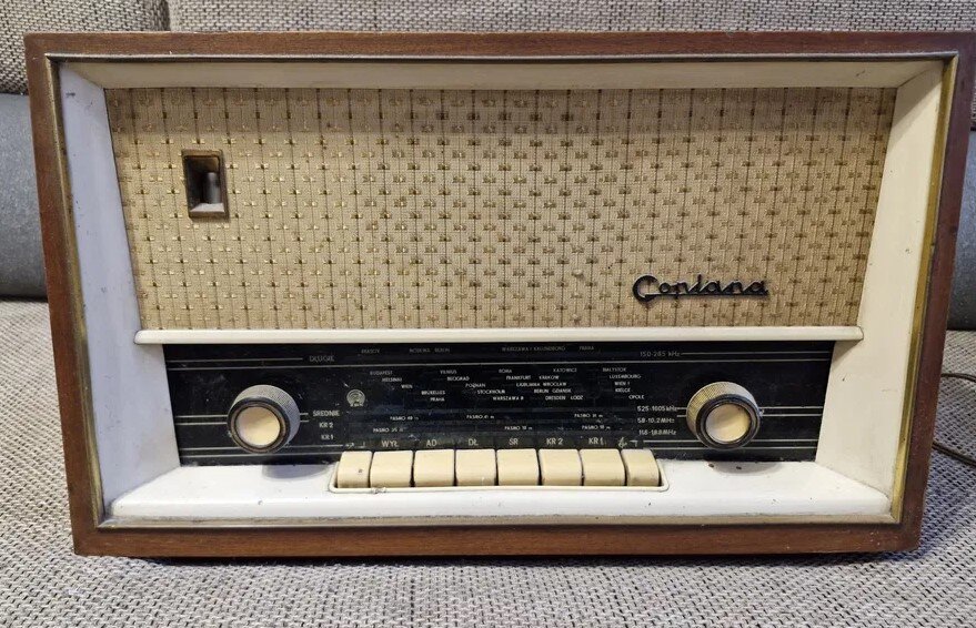 Dawny model odbiornika radiowego. Jest to sporych rozmiarów prostopadłościan, w drewnianej obudowie, górną połowę przedniego panelu zajmuje głośnik, poniżej są przyciski i pokrętła regulacji ustawień. Na głośniku widnieje nazwa radioodbiornika: Goplana.