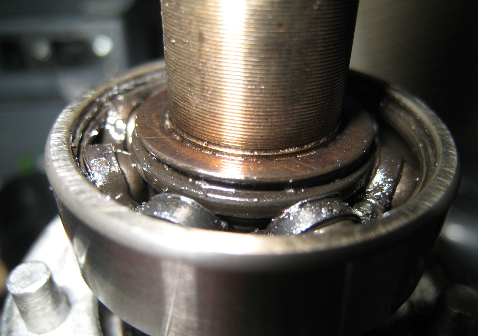 Fotografia przedstawia okrągły, żelazny, masywny przedmiot z kulkami i wystającym bolcem. To łożysko.