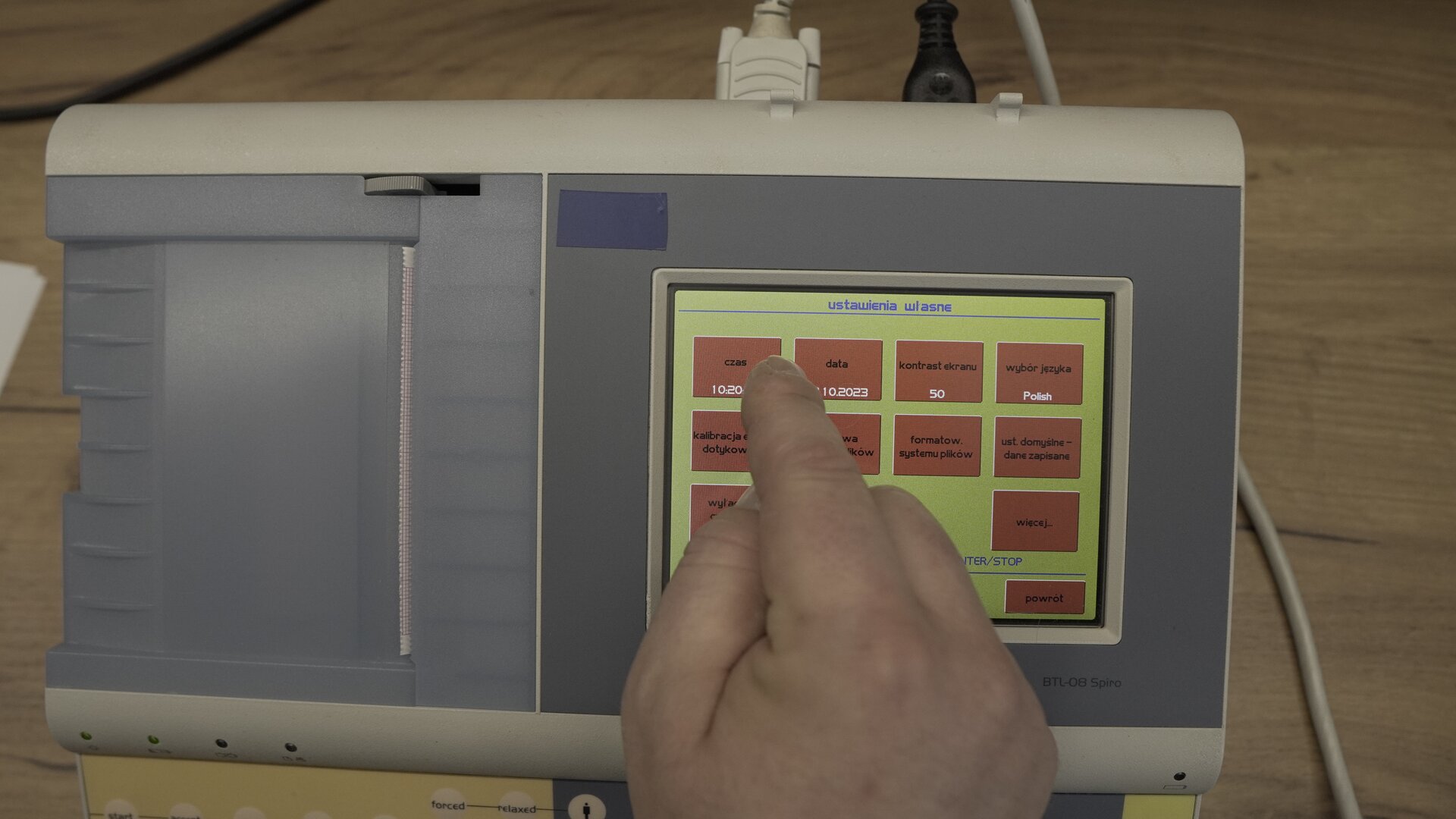 Na zdjęciu technik wybiera na klawiaturze ekranowej spirometru przycisk Czas.