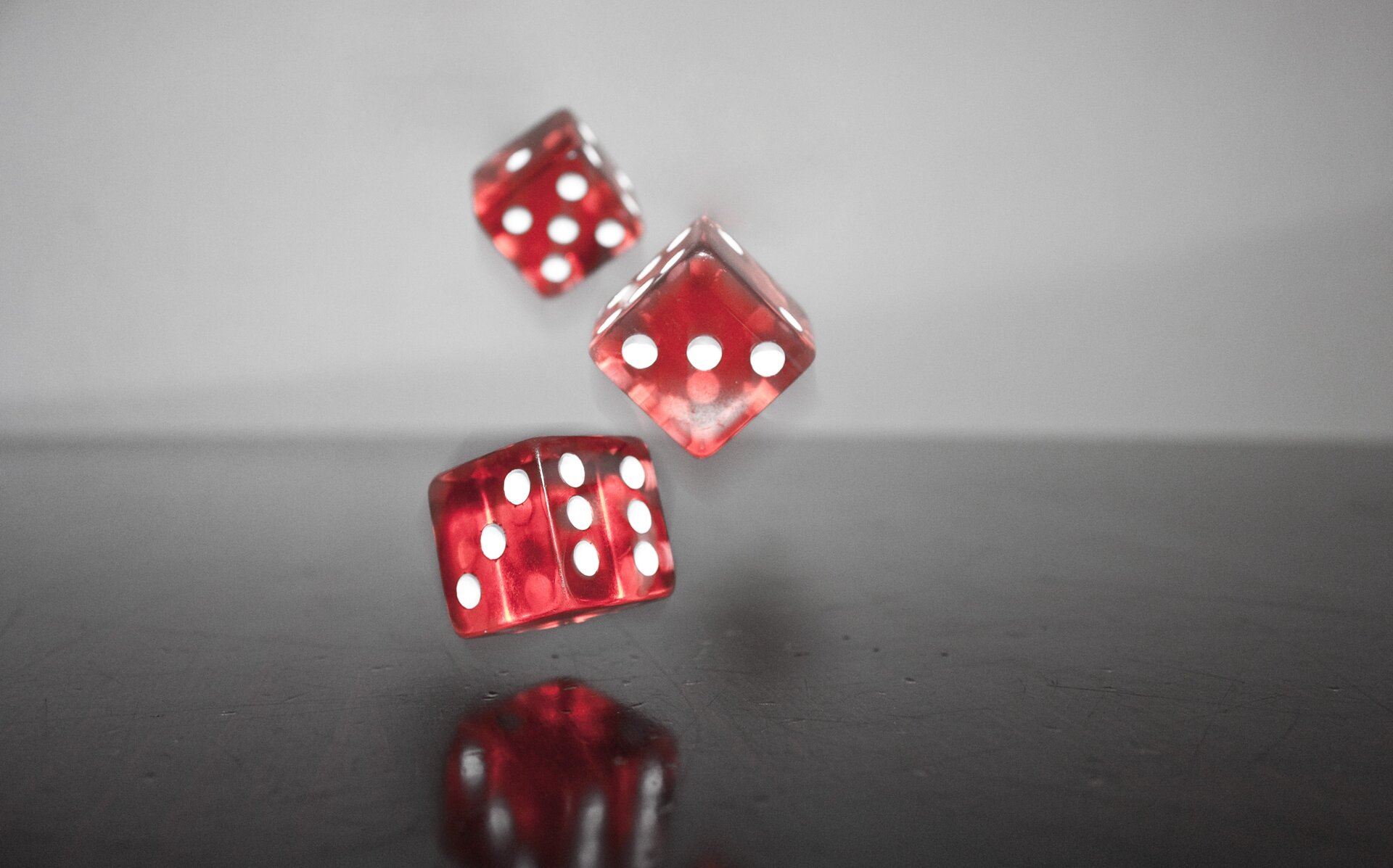 Zdjęcie przedstawia rzucone kostki do gry. Są to trzy czerwone kostki z białymi oczkami.