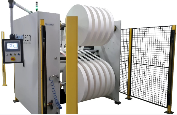 Grafika przedstawia bobiniarkę. Posiada ona dwa walce ze wstęgami. Bobiniarka przecina szeroką wstęgę na węższe i nawija je ponownie w zwój. Z boku urządzenia znajduje się panel sterujący.