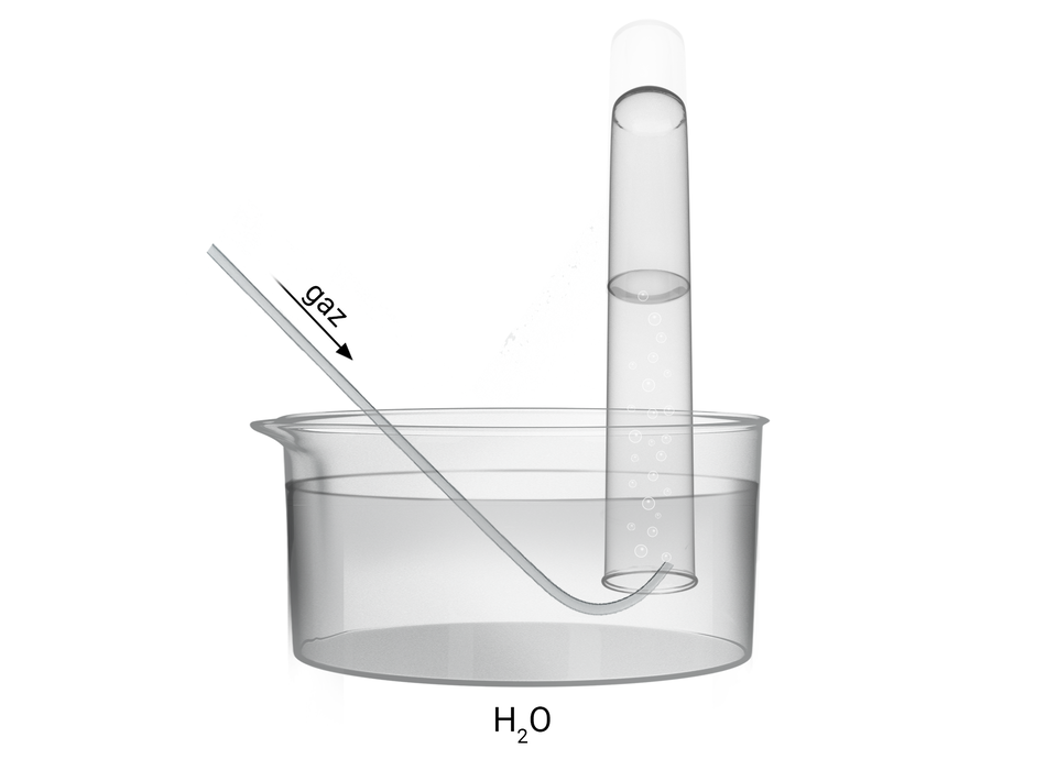 Ilustracja przedstawia krystalizator wypełniony wodą, w którym umieszczona została probówka do góry dniem, w taki sposób, że jest do połowy wypełniona wodą. W probówce umieszczona została końcówka szklanej rurki, którą do probówki dostaje się gaz.