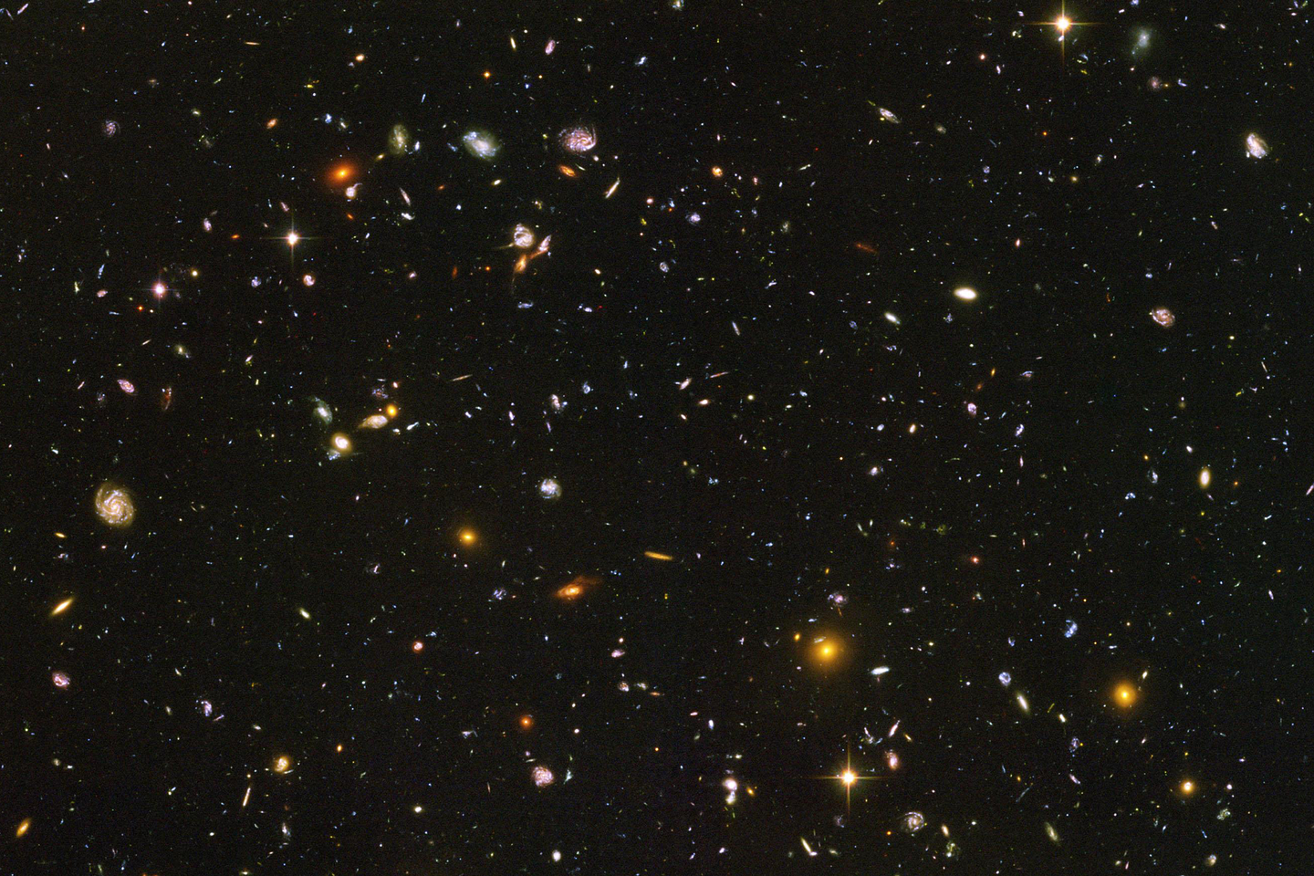 Fotografia wykonana z teleskopu umieszczonego w kosmosie. Na tle czarnego nieba widoczne liczne mniejsze lub większe punkty obrazujące galaktyki.