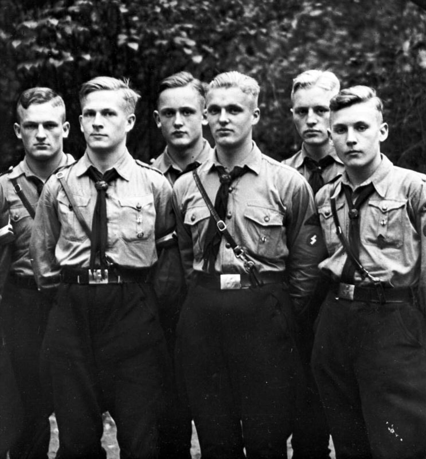 Fotografia czarno-biała przedstawiająca grupę Hitlerjugend. To sześciu młodych chłopców. Ubrani są w mundury: koszula lniana, krawat, spodnie wojskowe przepasane paskiem.