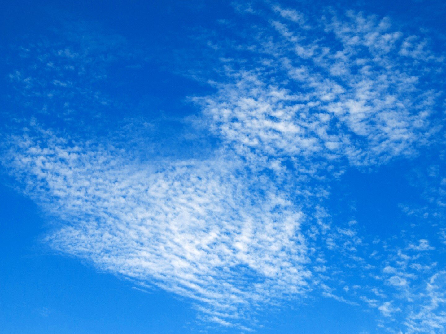 Fotografia przedstawia chmury na niebie. Są one białe, rozległe, kłębiasto-pierzaste