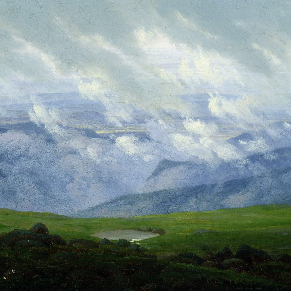 Obraz przedstawia zbocze góry porośnięte trawą. Na drugim planie gęste chmury opadają na nagie góry.