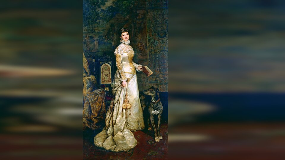 Obraz przedstawia młodą kobietę w okazałej biało‑złotej długiej sukni z welonem. Kobieta w lewej ręce trzyma otwartą książkę. Obok stoi duży czarny pies w obroży.