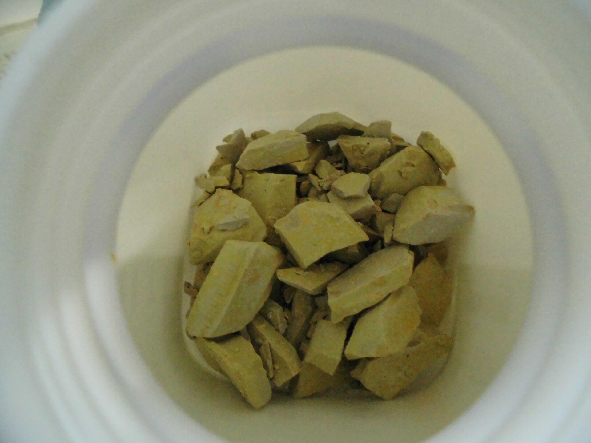 Zdjęcie przedstawia wnętrze fiolki z siarczkiem potasu w postaci zielono–żółtych grudek.