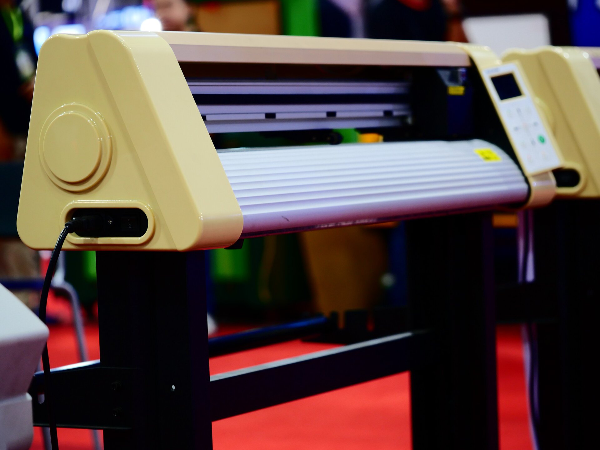 Na zdjęciu przedstawiono laminator. Urządzenie ma kształt poziomej belki. W centralnej części znajduje się szczelina, do której wsuwa się laminowany arkusz papieru.