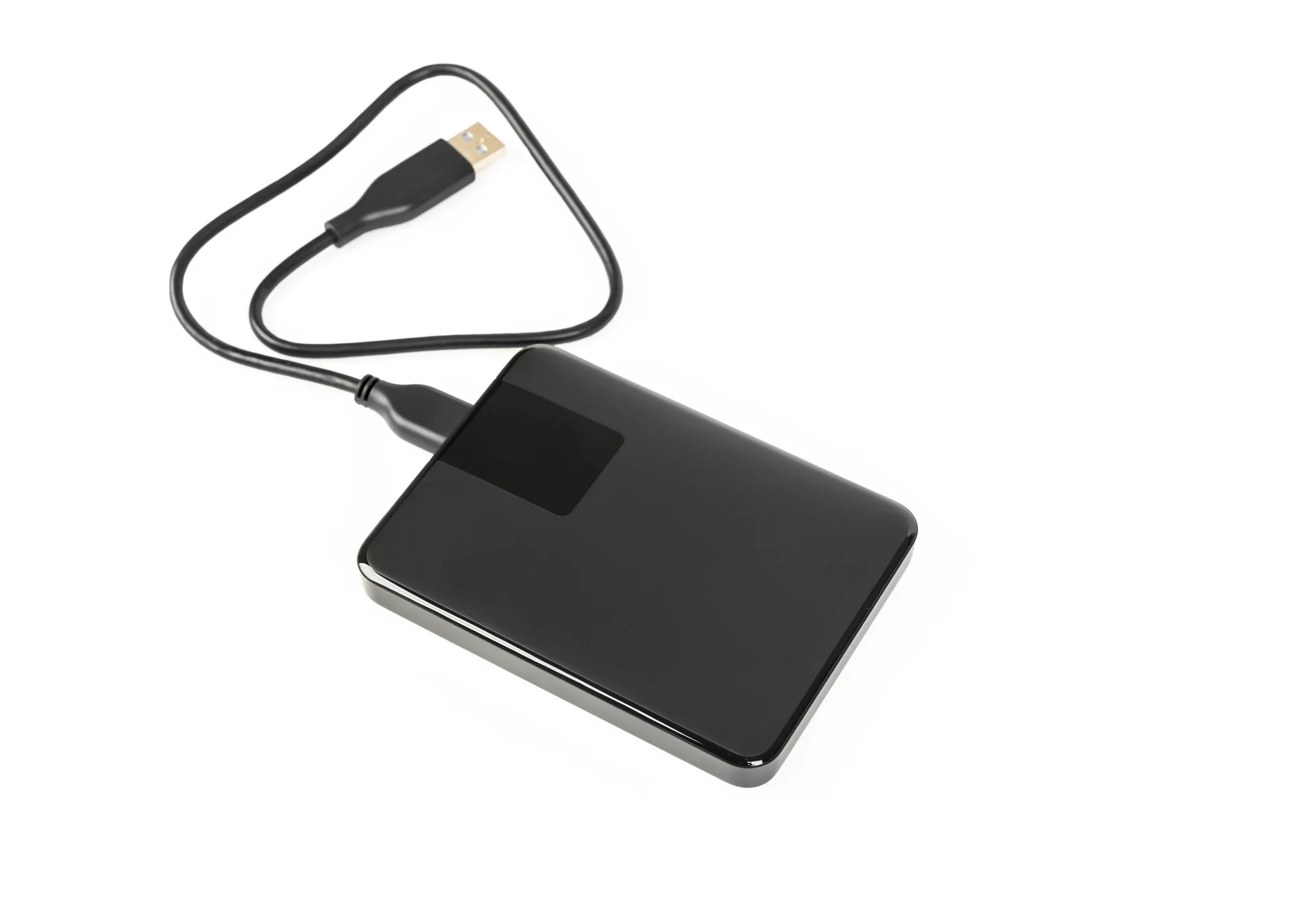 Fotografia przedstawiająca dysk zewnętrzny w obudowie zewnętrznej z podpiętym kablem USB. 