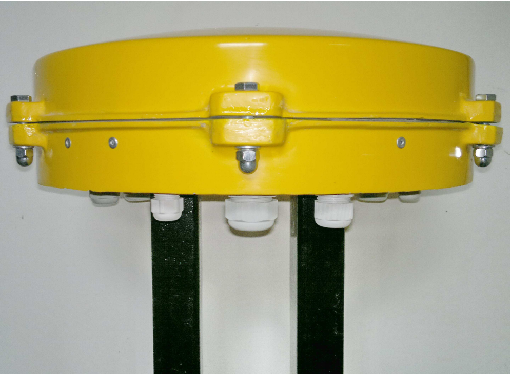 Ilustracja przedstawia garnek kablowy. Składa się on z żółtej dwuczęściowej pokrywy łączeniowej, którą łączy się przy pomocy śrub oraz wspornika. 