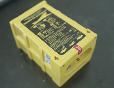 Zdjęcie pokazuje sygnalizator sygnałów awaryjnych. Jest to niewielkie żółte prostopadłościenne pudełko z napisami na górnej podstawie.