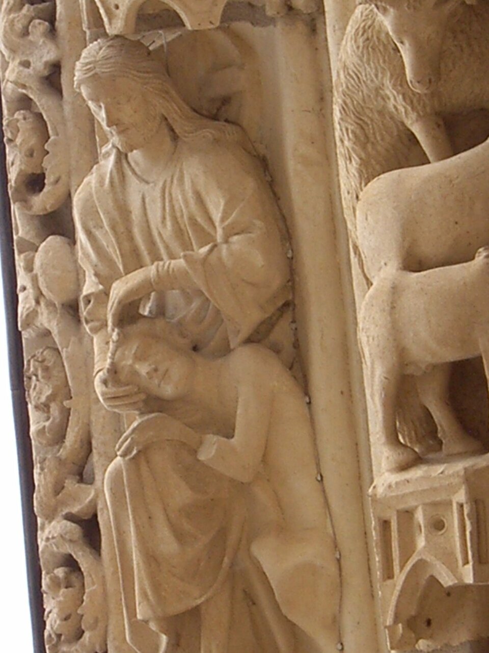 Ilustracja przedstawia scenę biblijną stworzenia Adama: wyższa postać jest przedstawieniem Stwórcy, na jego kolanach opiera się postać mężczyzny. Jest to detal z archiwolty portalu północnego katedry w Chartres we Francji.