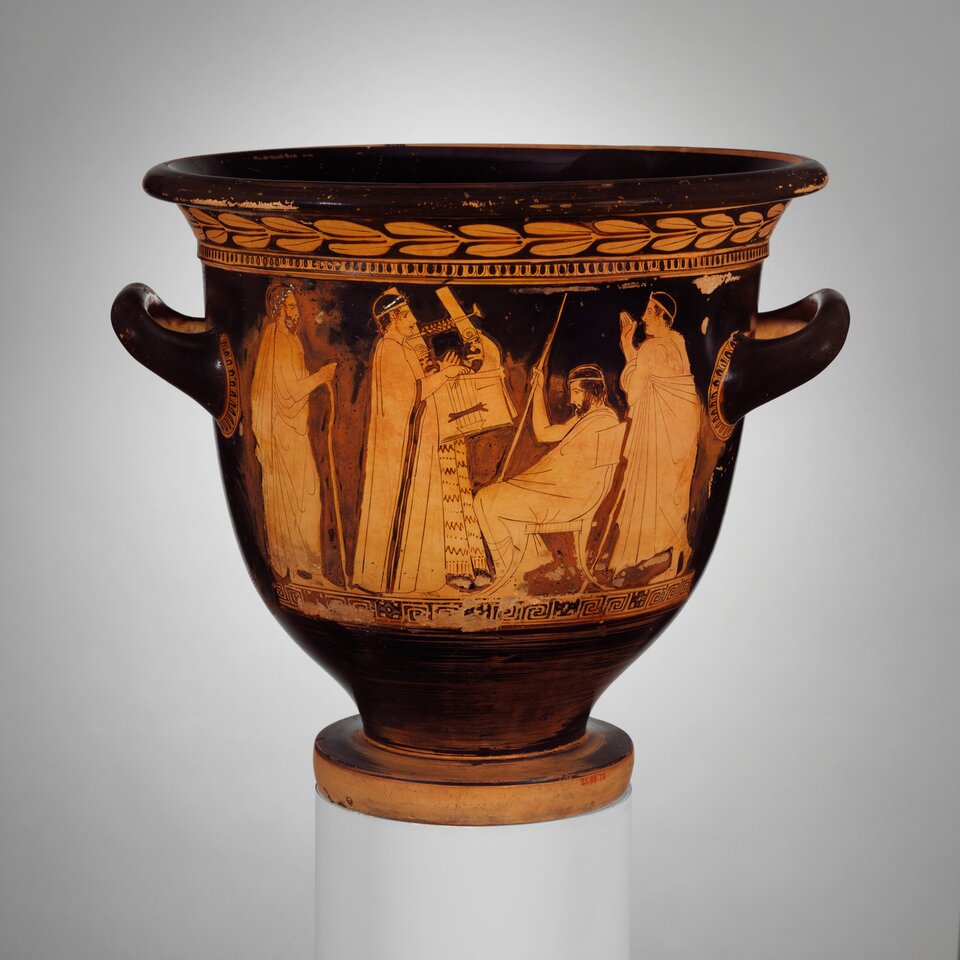 Ilustracja przedstawia krater dzwonowaty Polignota z Thasos, „Krater z młodzieńcami grającymi na lirze”. Widoczne jest naczynie o szerokim, zaokrąglonym korpusie z dwoma uchwytami po bokach. Na jego powierzchni znajduje się czerwonofigurowa dekoracja przedstawiająca kilka postaci w długich szatach; po lewej stronie siedzący młodzieniec trzyma lirę, obok niego stoją dwie postacie zwrócone w jego stronę, a po prawej widoczne są kolejne dwie postacie w pozycji stojącej. U dołu naczynia biegnie pas geometrycznych ornamentów, a przy górnej krawędzi znajduje się dekoracja z motywem liści.