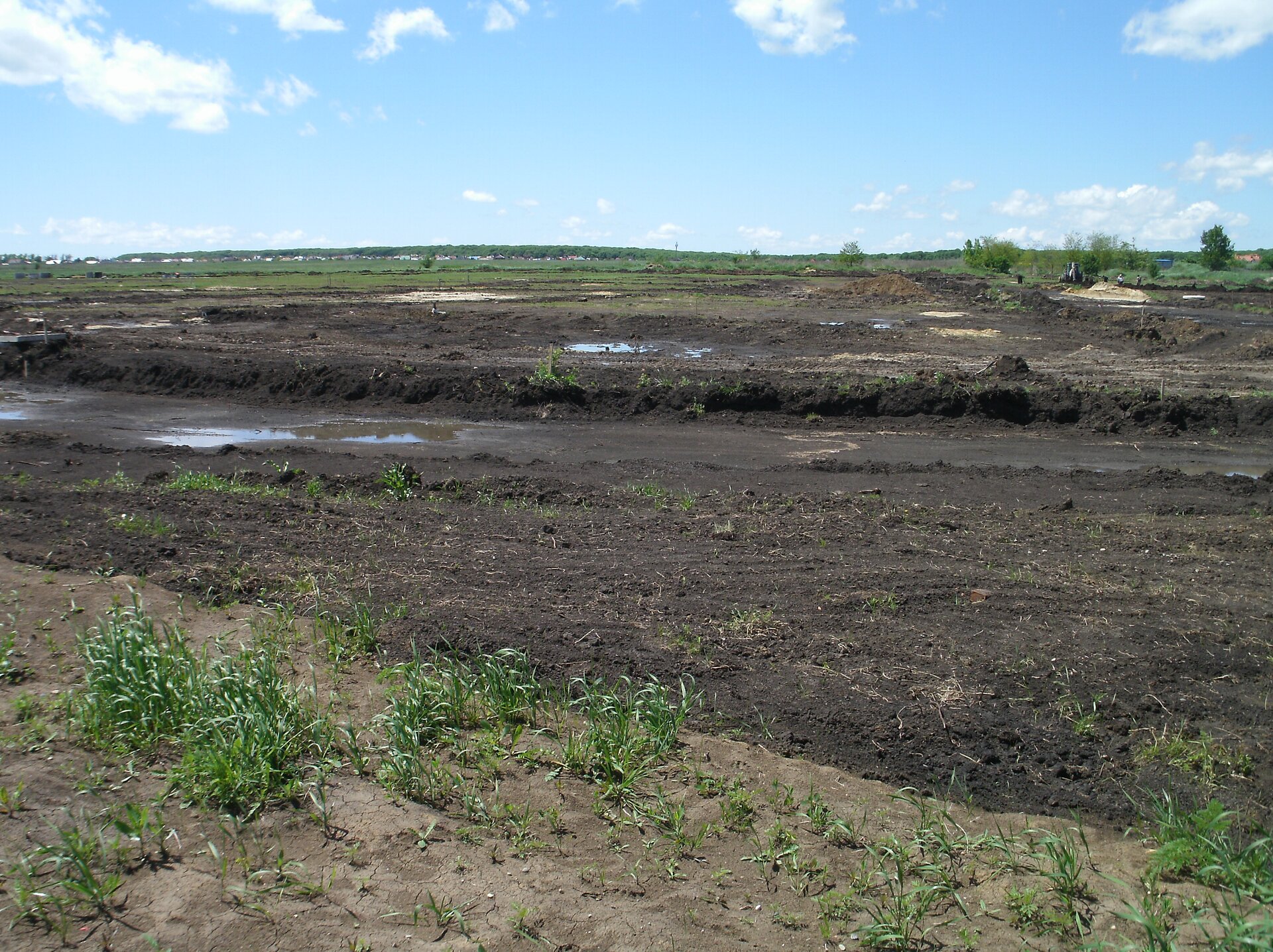Na zdjęciu pole, ziemia jest czarna, w nie których miejscach delikatnie porośnięta trawą.