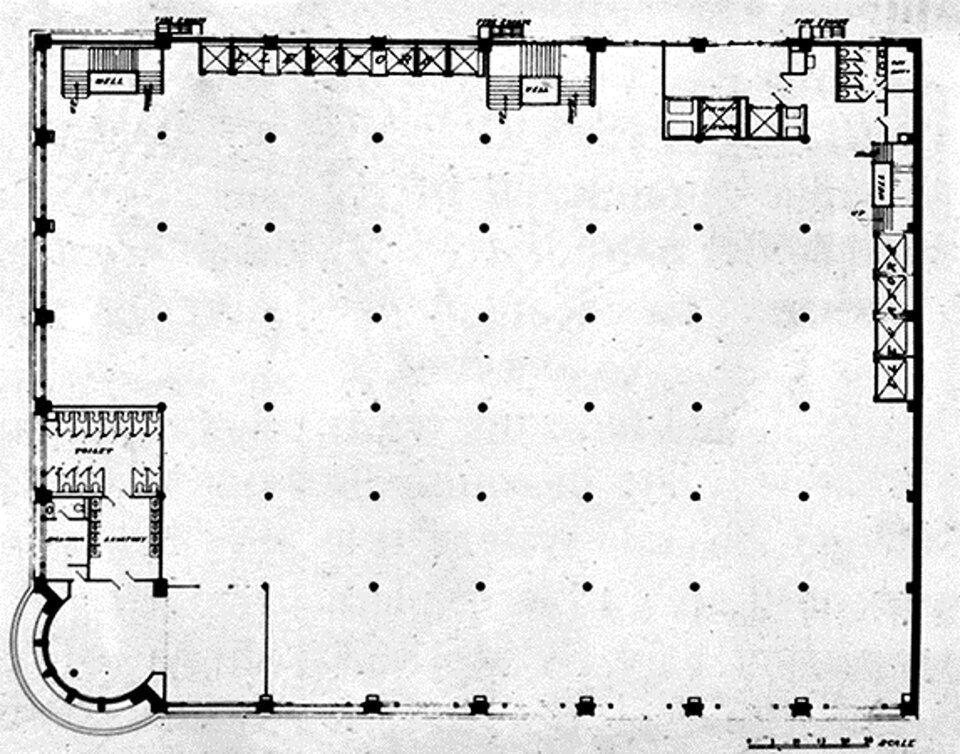 Ilustracja przedstawia rzut techniczny planu Carson, Pirie, Scott Building w Chicago. Czarno‑biały rysunek techniczny przedstawiający plan kondygnacji dużego budynku. Większość powierzchni zajmuje otwarta, prostokątna hala podzielona regularnym układem kolumn oznaczonych czarnymi punktami. Wzdłuż ścian rozmieszczono klatki schodowe, windy oraz pomieszczenia pomocnicze, w tym toalety. W lewym dolnym narożniku znajduje się półkolisty hol wejściowy połączony z niewielkim zespołem pomieszczeń. Rysunek wykonano w formie rzutu architektonicznego z zaznaczonymi ścianami, przejściami i elementami konstrukcyjnymi.