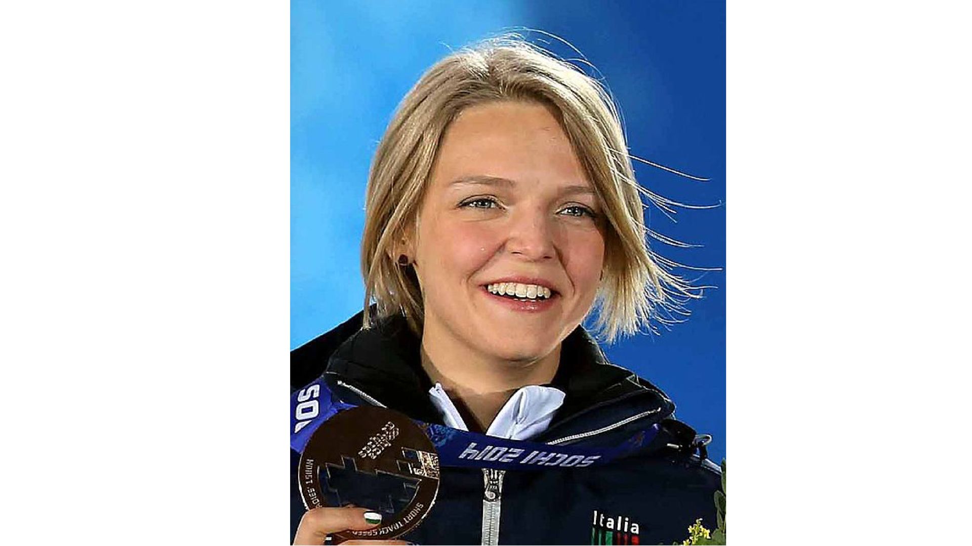 Na zdjęciu znajduje się włoska mistrzyni olimpijska Arianna Fontana z medalem w ręku. Kobieta jest uśmiechnięta.