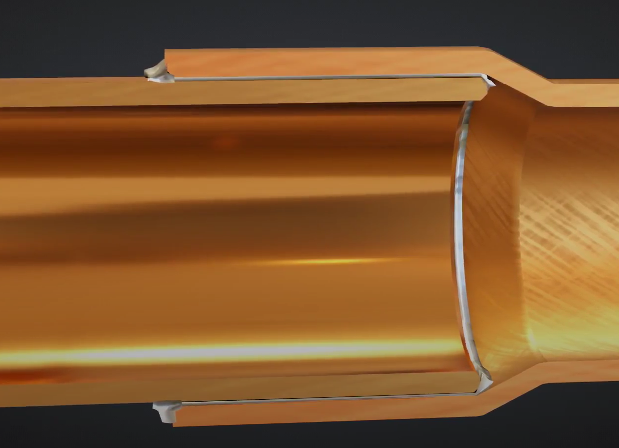 Grafika przedstawia przekrój dwóch miedzianych rur połączonych metodą lutowania twardego. Jedna z rur, o mniejszym przekroju, włożona jest w większą i obie połączone są lutem w kolorze srebrnoszarym. Widoczne jest miejsce połączenia rur.