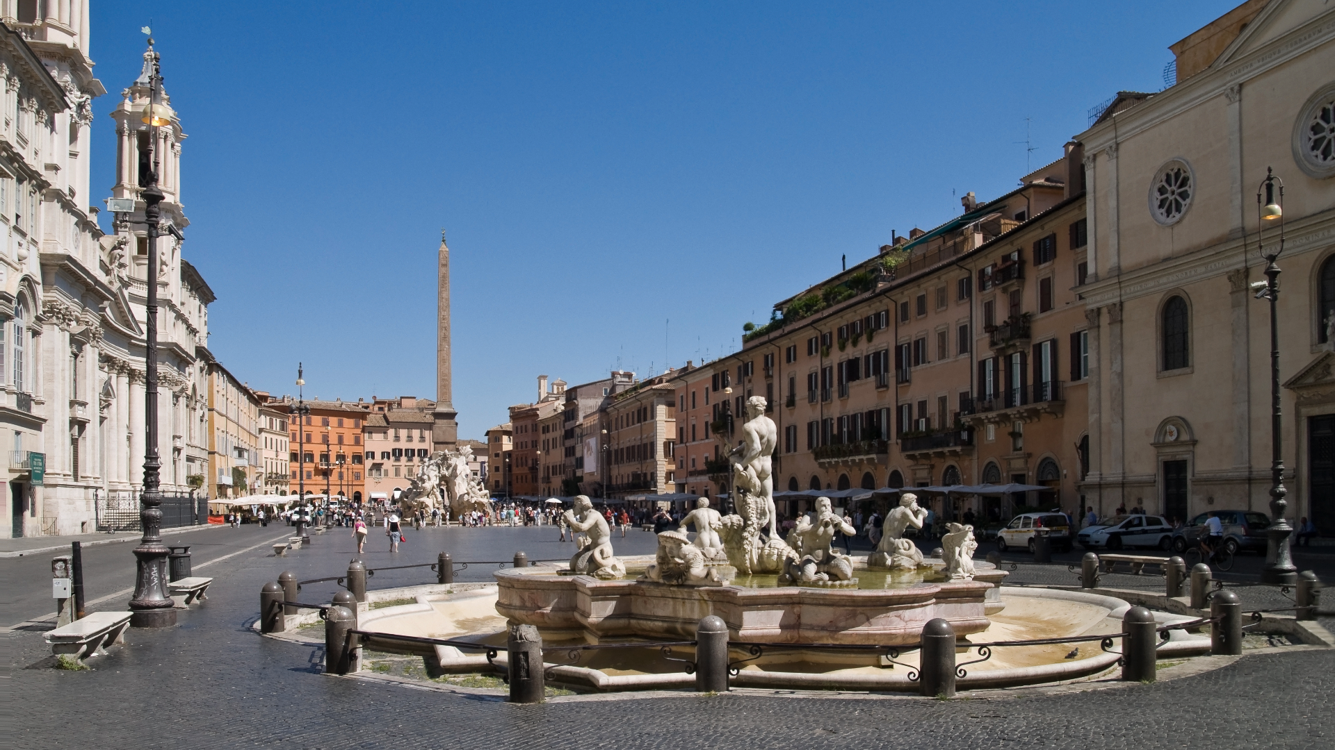 Zdjęcie przedstawia plac Navona. Na placu znajduje się fontanna z figurami. Wokół placu widoczne są włoskie kamienice.