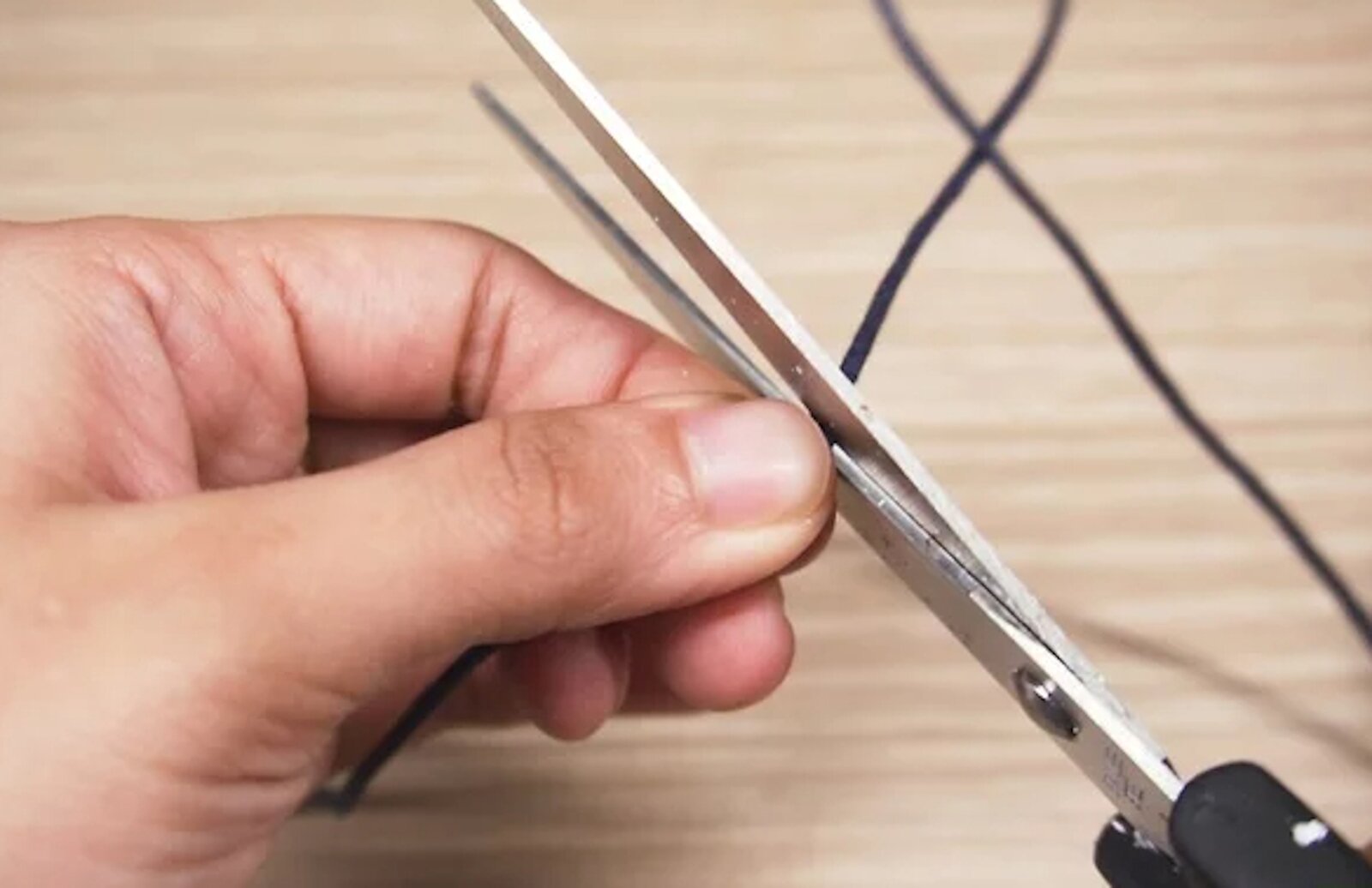 Zdjęcie przedstawia człowieka tnącego sznurek.