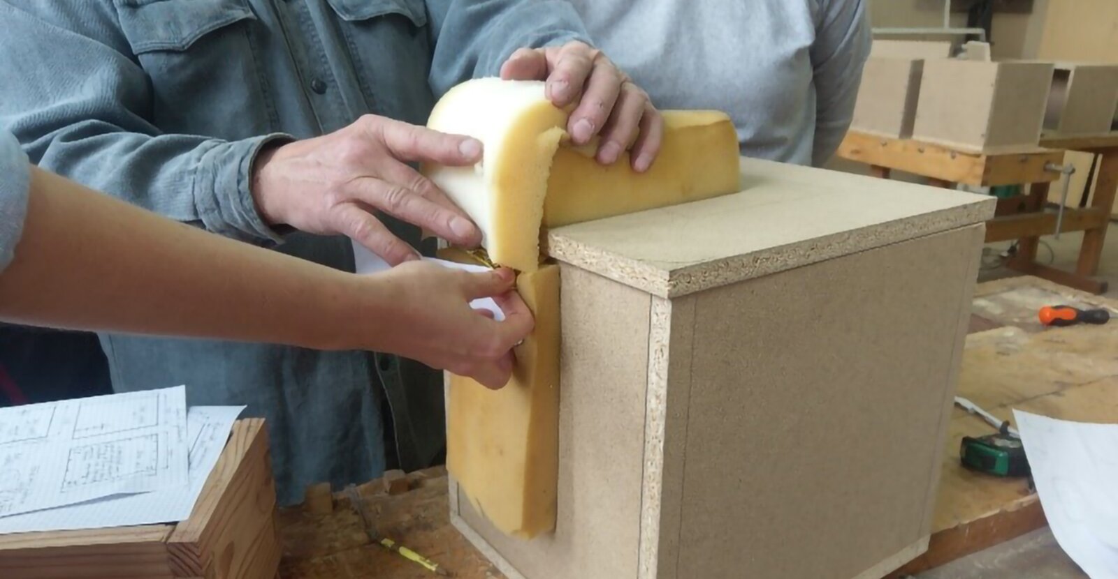 Na zdjęciu widzimy gotową skrzynię pufa. Tapicer obkłada ją pianką tapicerską.