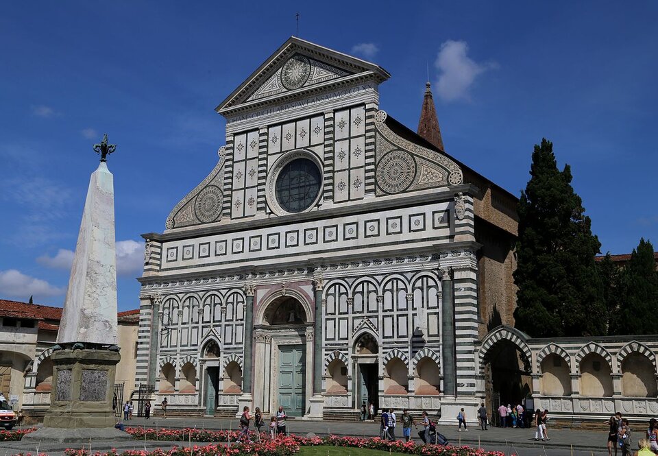 Fotografia przestawia front kościoła Santa Maria Novella we Florencji. Zielone, białe i różowe marmurowe płyty dzielą elewację na mniejsze pola. Górną część, zwieńczoną tympanonem, ograniczają dwie duże woluty, które w łagodny sposób łączą wysoki front nawy głównej ze znacznie niższymi nawami bocznymi. Pośrodku górnej części elewacji umieszczono duże okno – tzw. rozetę, poniżej znajduje się duży portal ozdobiony herbami rodziny Rucellaich, mecenasów kościoła. Do kościoła prowadzi troje drzwi. Po prawej stronie, do budynku kościoła przylega murowane ogrodzenie ozdobione biało‑zieloną arkadą, za którym rosną wysokie drzewa. Po lewej stronie stronie stoi obelisk w kształcie stożka, zakończony lilią. Przed kościołem klomb kwiatowy.