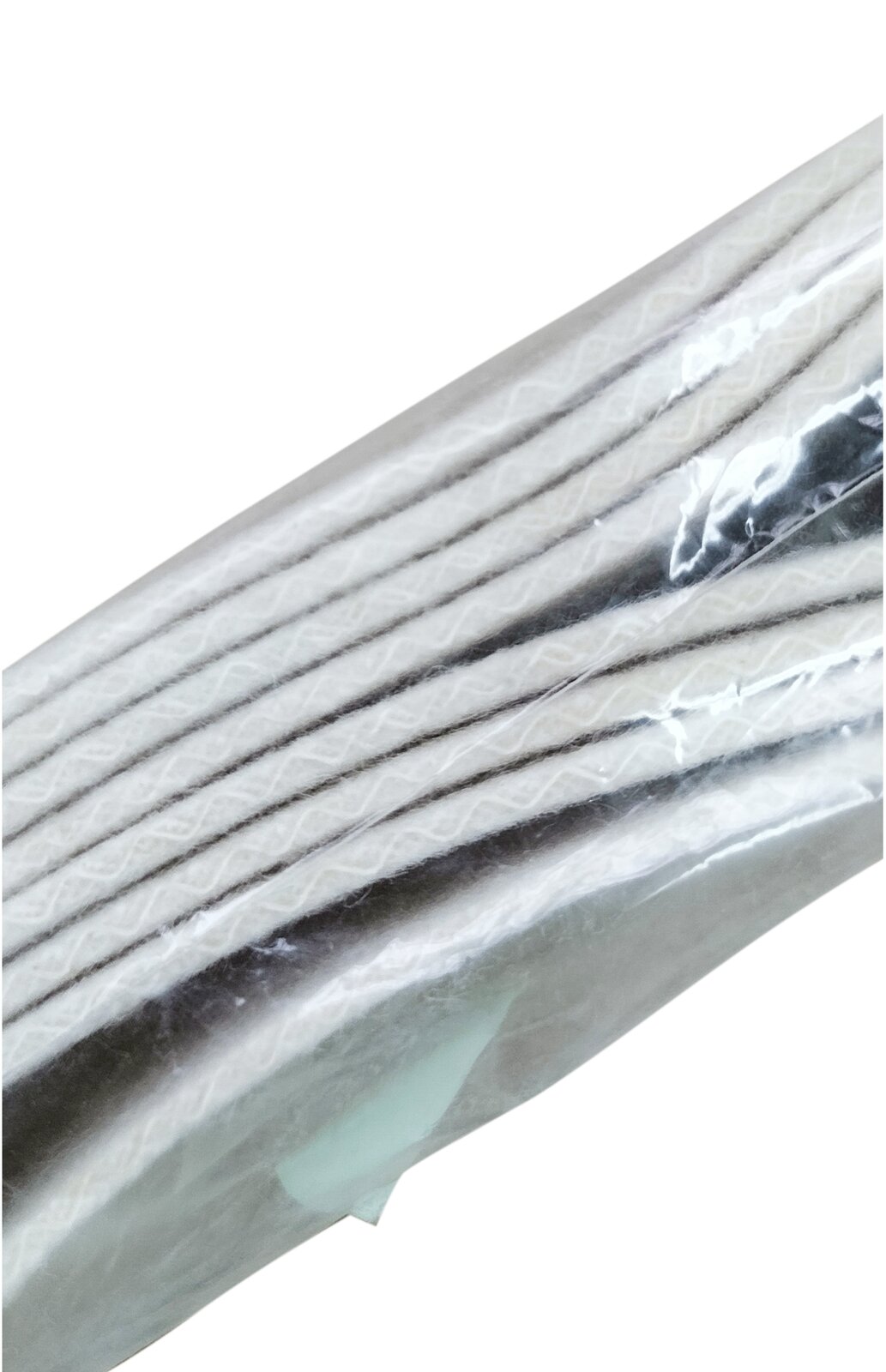 Zdjęcie przedstawia filc tkany. Widoczne są płaty białego filcu w ujęciu z boku, w przeźroczystym foliowym opakowaniu.