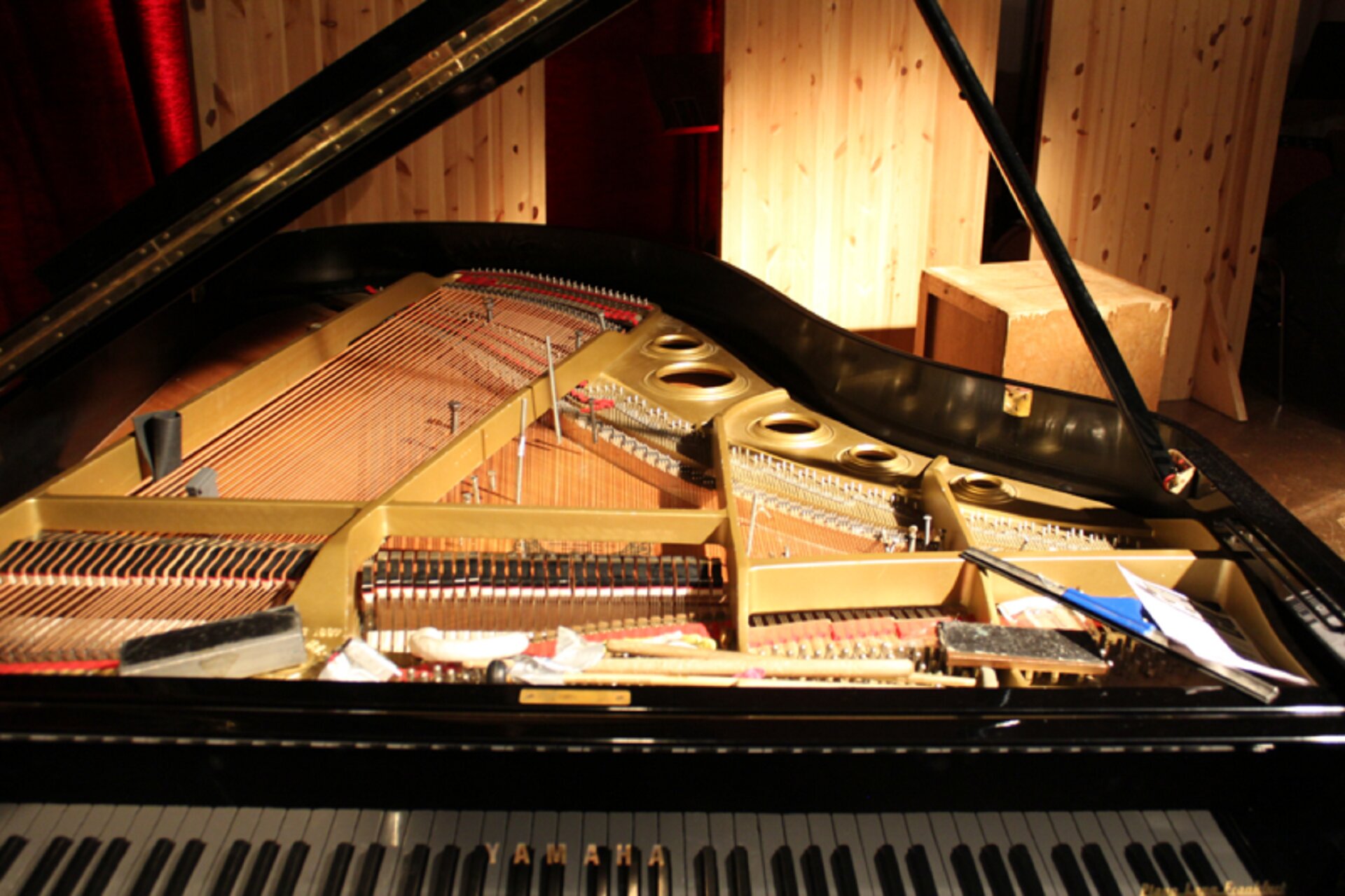 Fotografia przedstawia fortepian preparowany. Klapa fortepianu jest podniesiona i widać cały środek instrumentu.