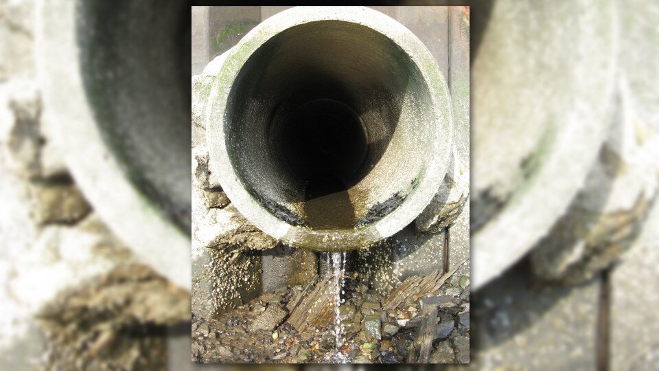 Ilustracja przedstawia rurę ściekową, z której wydostaje się woda.