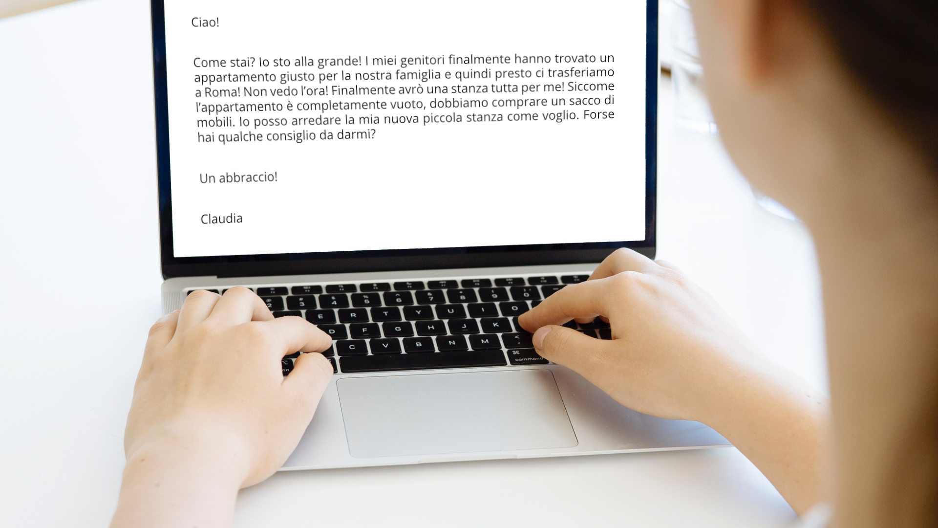 Zdjęcie przedstawia osobę siedzącą przed laptopem, widoczny jest tylko kawałek jej głowy i ręce trzymane na klawiaturze. Na ekranie znajduje się napisany mail. 
Ciao! 
Come stai? Io sto alla grande! I miei genitori finalmente hanno trovato un appartamento giusto per la nostra famiglia e quindi presto ci trasferiamo a Roma! Non vedo l’ora! Finalmente avrò una stanza tutta per me! Siccome l’appartamento è completamente vuoto, dobbiamo comprare un sacco di mobili. Io posso arredare la mia nuova piccola stanza come voglio. Forse hai qualche consiglio da darmi? 
Un abbraccio! 
Claudia

