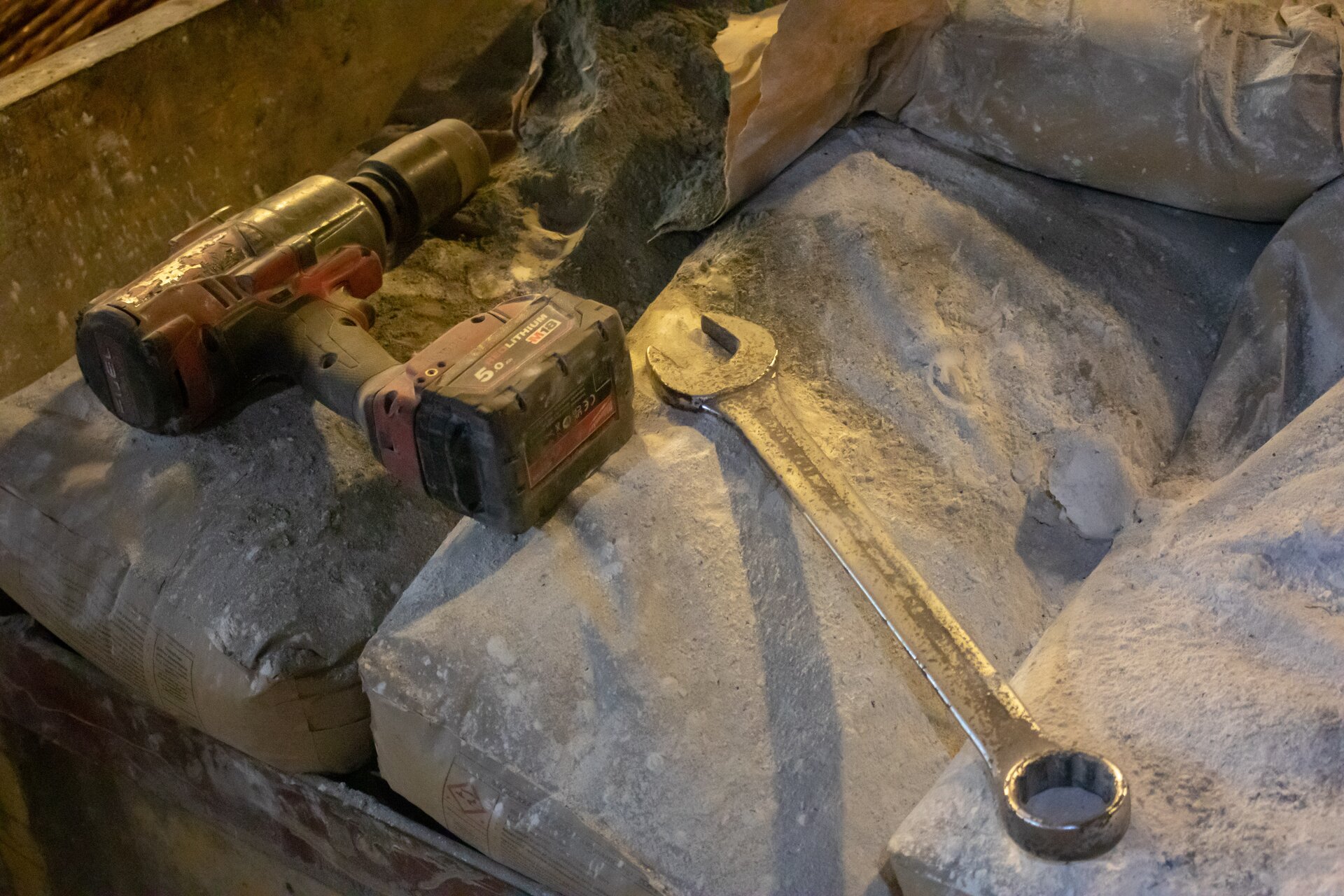 Na zdjęciu widoczny jest klucz elektryczny. Klucz przypomina kształtem pistolet. Różnicę z pistoletem stanowi organ roboczy. Lufa klucza jest o kształcie cylindra. Widoczny na zdjęciu cylinder jest długi i podobnej średnicy co klucz elektryczny.Po prawej stronie klucza elektrycznego leży klucz ślusarski. Podstawa klucza ślusarskiego to podłużny prostokąt. Na obu końcach prostokąta znajdują się zakończenia o kształcie litery U Widoczne na zdjęciu klucze leżą na workach. 