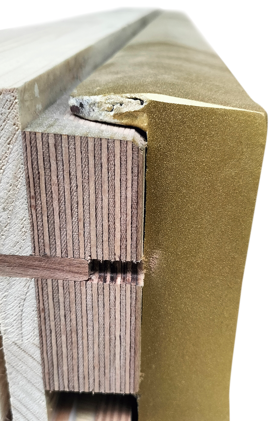 Zdjęcie przedstawia fragment strojnicy i ramy żeliwnej pianina z boku. Strojnica jest wykonana ze sklejki w kolorze jasno i ciemnobrązowym. Rama żeliwna po prawej jest w kolorze starego złota.