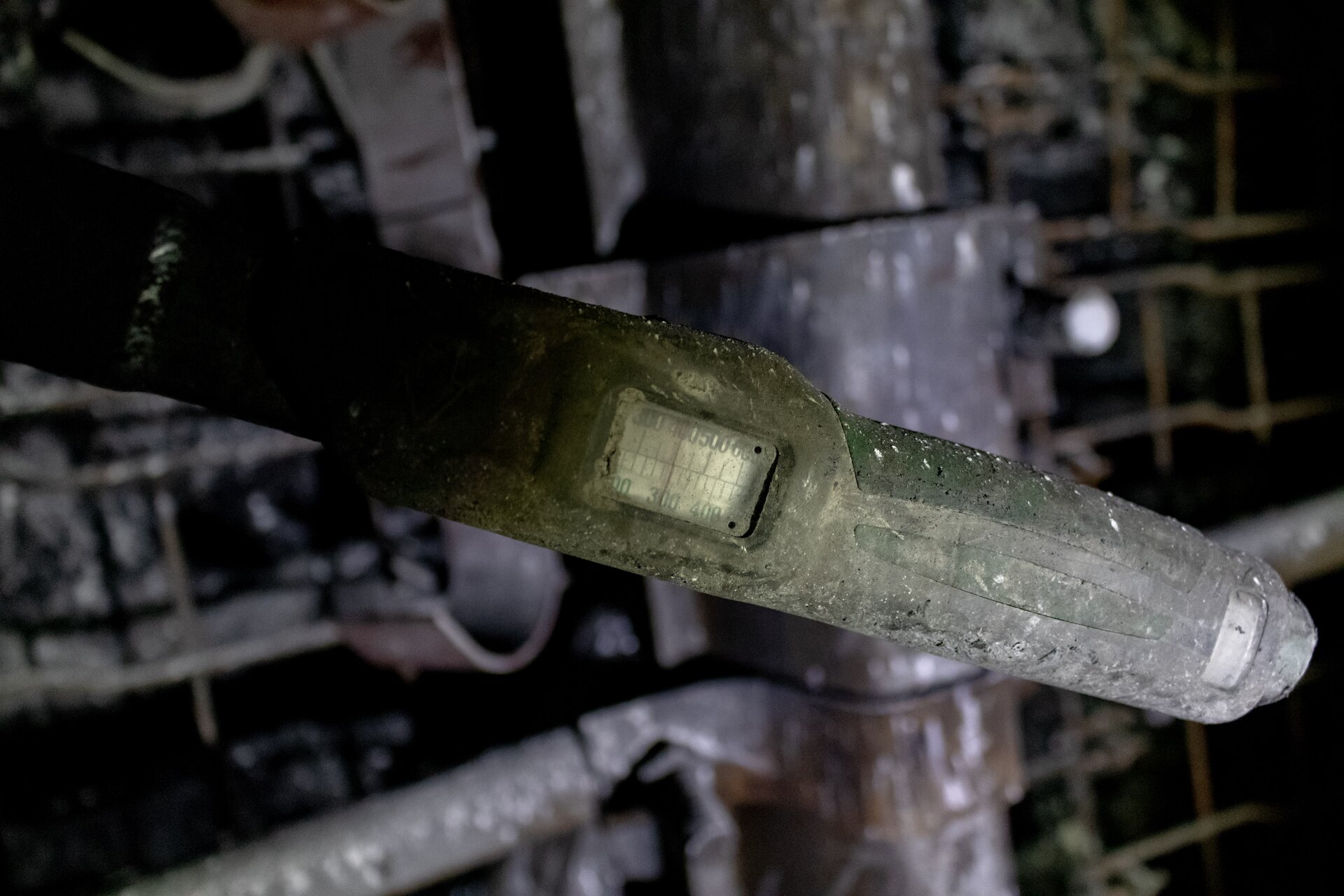 Na zdjęciu widać końcówkę klucza dynamometrycznego. Centralnym elementem zdjęcia jest fragment klucza. Po prawej stronie klucza na jego końcu widoczny jest wskaźnik. Wskaźnik znajduje się za szybką. Na wskaźniku widać skalę. W tle widać fragment zabezpieczonego ociosu.