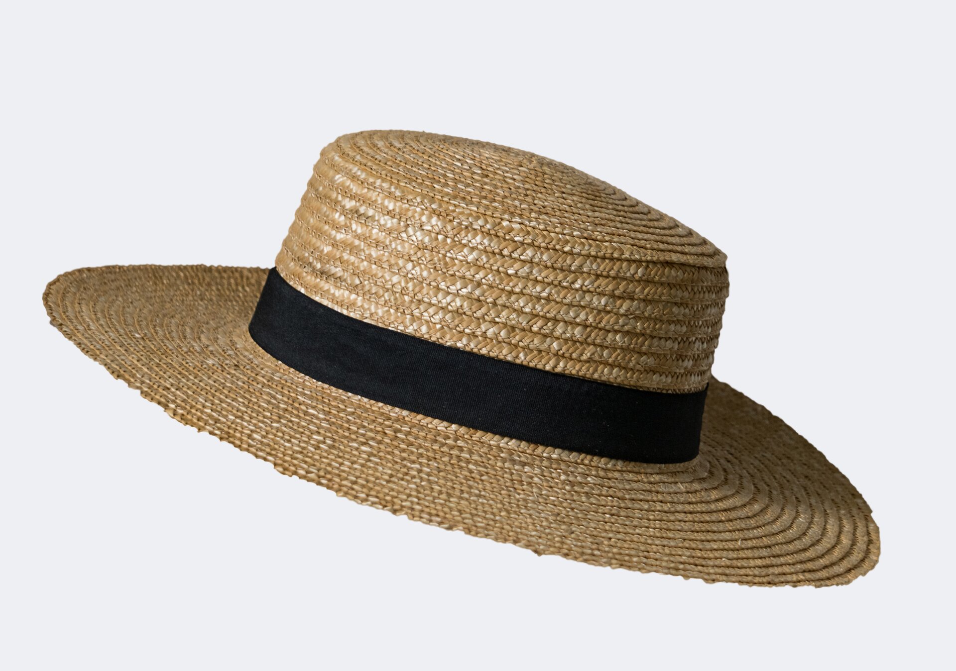 Zdjęcie kapelusza słomkowego z dużym rondem i ozdobną czarną wstążką. 