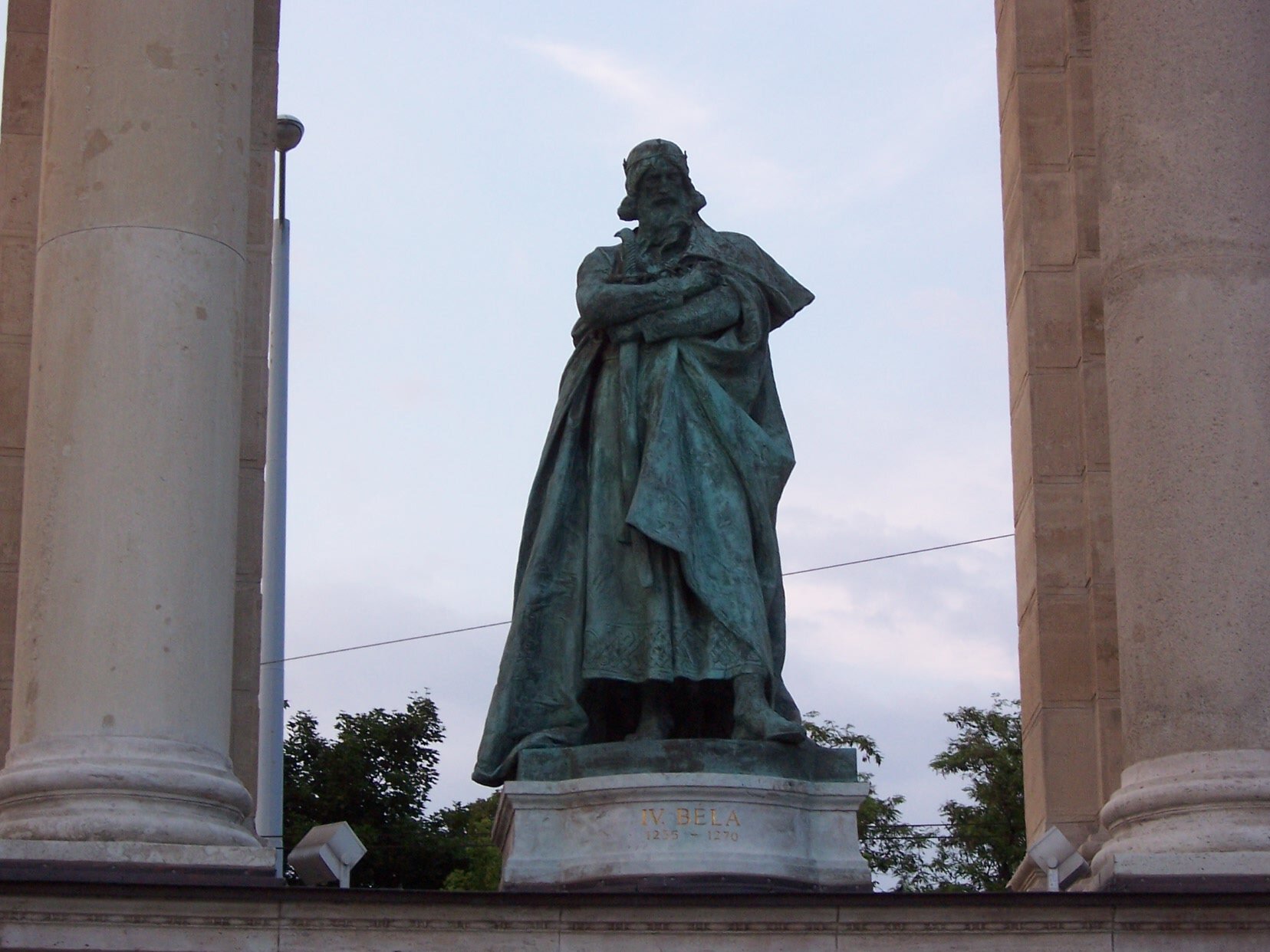 Zdjęcie przedstawia pomnik w brązie, na którym widnieje postać starszego mężczyzny. Mężczyzna ma koronę na głowię, spod której widać dłuższe włosy. Ma także wąsy i długa brodę. Ubrany jest w długi, powłóczysty płaszcz, którego połami się okrywa. Obie ręce złożone ma na piersiach. Pomnik stoi na jasnym cokole, na którym widnieje napis: 4 Bela.