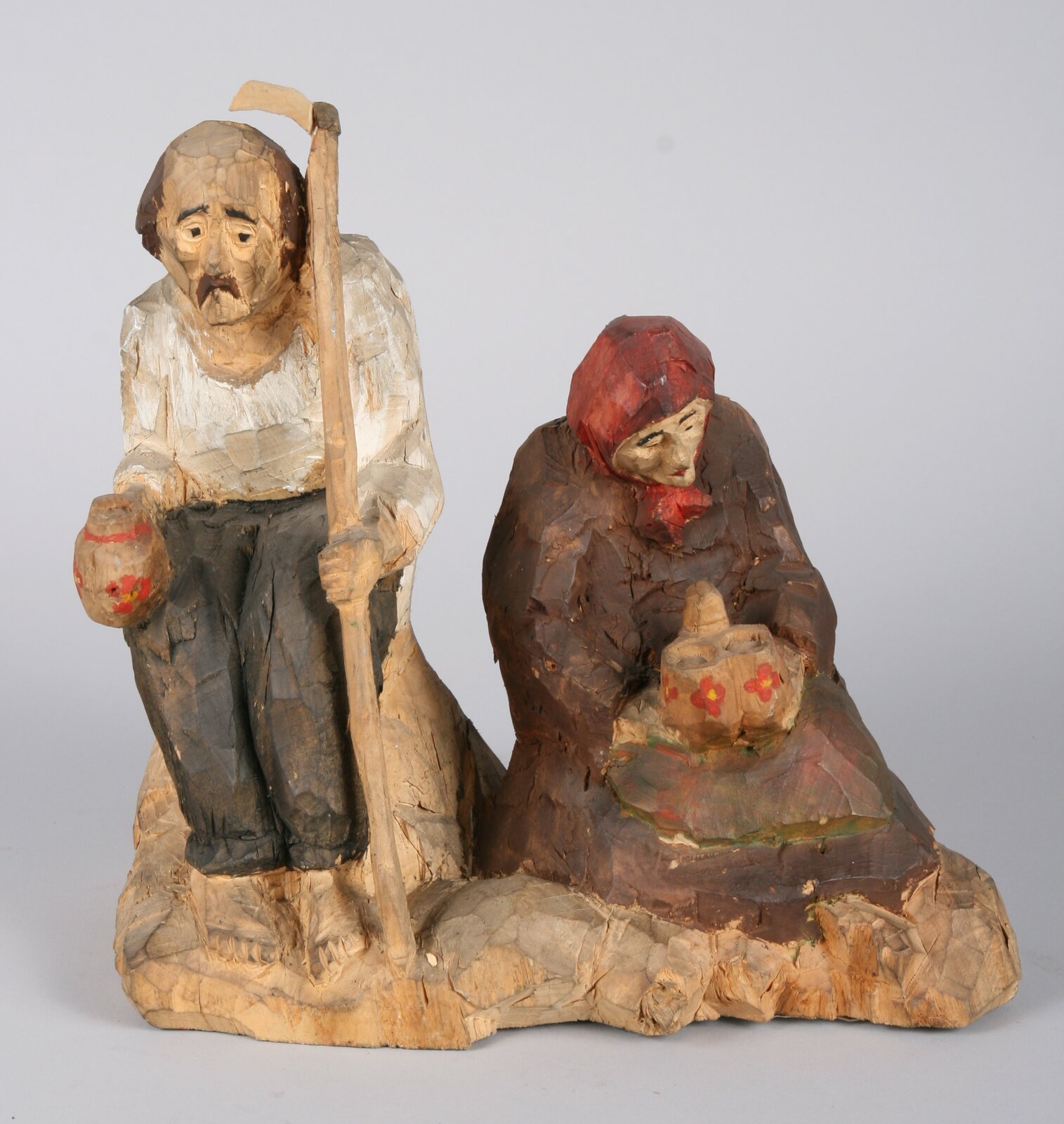 Rzeźba drewniana przedstawia dwóch żniwiarzy - kobietę i mężczyznę. Mężczyzna siedzi na podwyższeniu. W lewej ręce ma kosę, a w prawej - dzban z namalowanym czerwonym kwiatem. Ma bose stopy, szare spodnie i białą koszulę z długim rękawem. Ma łysy czubek głowy, a na bokach brązowe włosy. Ma wąsy. Jego twarz jest niesymetryczna - struktura drewna jest nierówna, lewe oko i brew jest niżej niż prawe. Kobieta siedzi po jego lewej stronie. Siedzi ona niżej, jakby na kolanach. Ma długą, brązową suknię, czerwona chustę na głowie. Jej twarz jest zwrócona w dół. W obu rękach trzyma na kolanach naczynie złożone z dwóch wysokich komór. Ozdobione jest malunkiem czerwonych kwiatów.